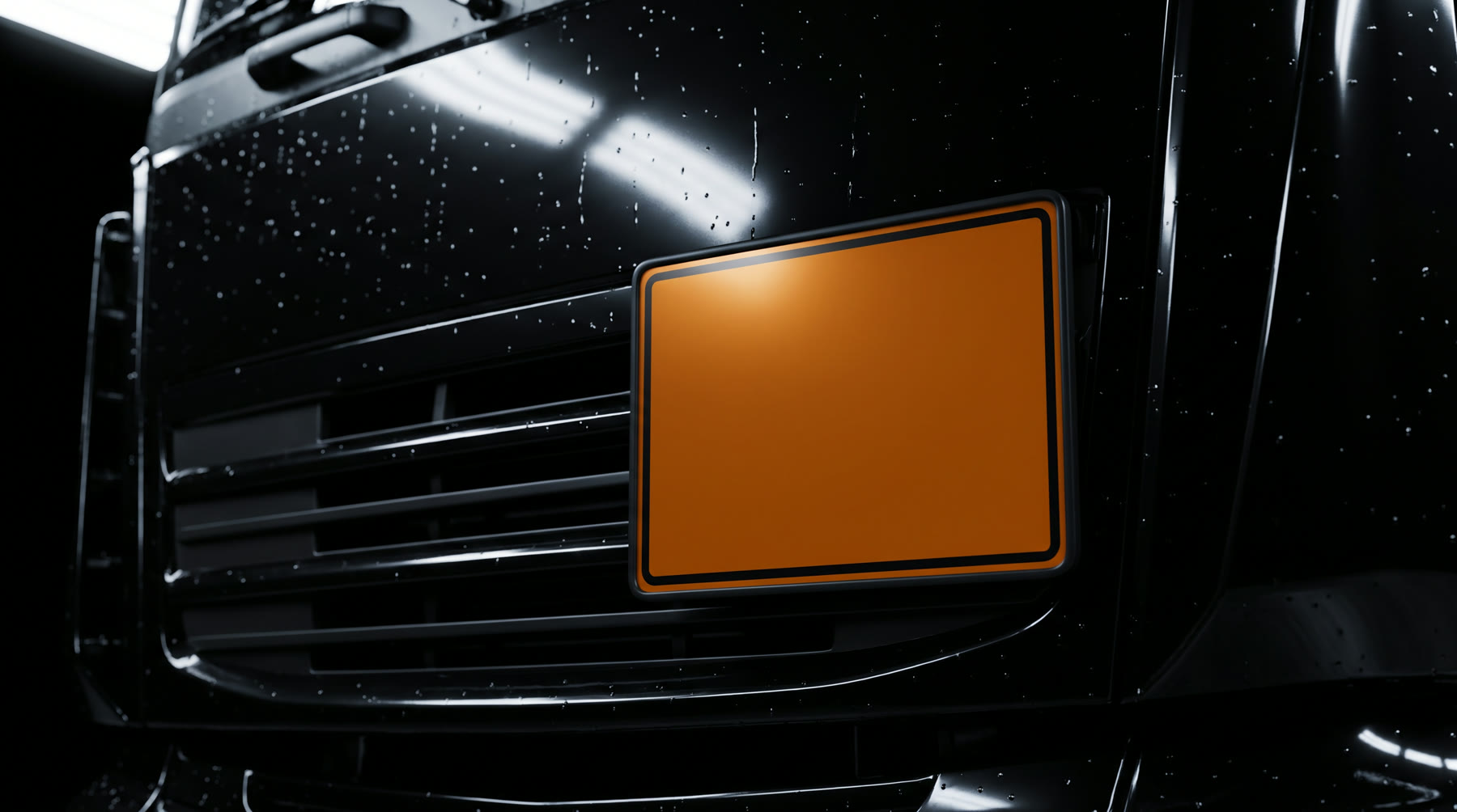 Orange Warntafel an der schwarz glänzenden Front eines LKW, Regentropfen auf dem Lack